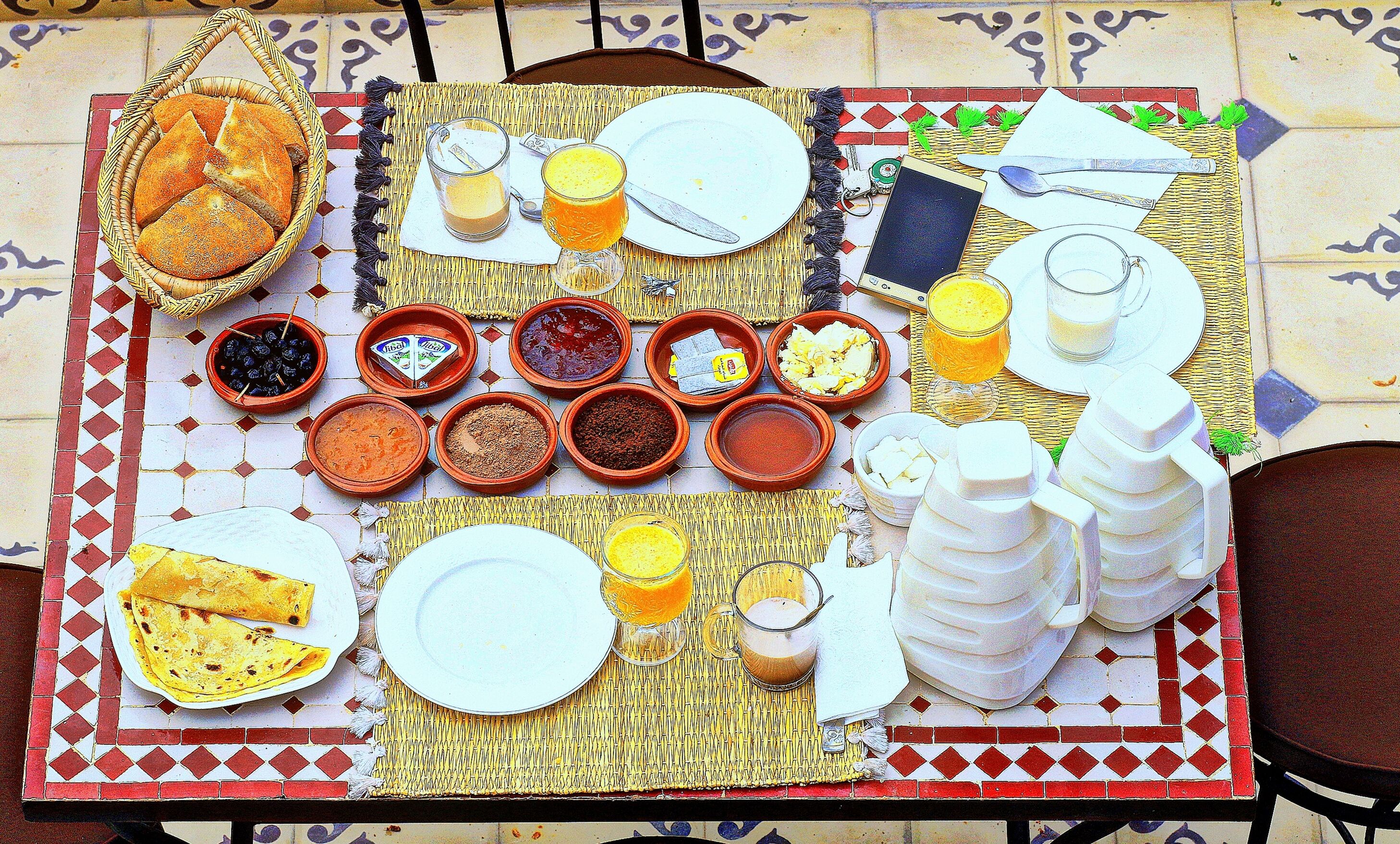 A breakfast spread on a table with various dishes, drinks, and utensils.