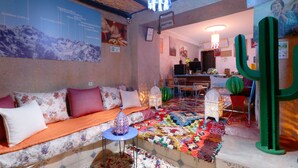 A cozy room with a sofa, a patterned rug, and a cactus decoration. - Toubkal Garden Hotel (Asni)