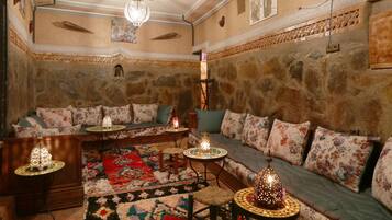 A cozy living room with a stone wall, a wooden sofa, and a patterned rug.