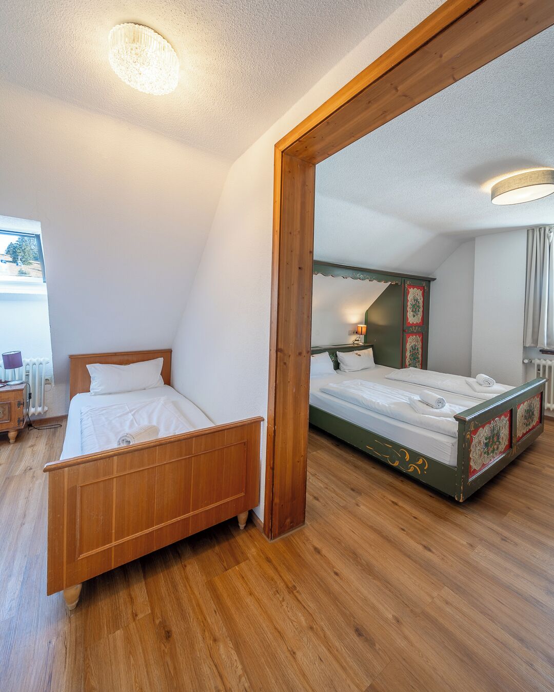 Une chambre à coucher avec un lit en bois, une armoire à miroir et un luminaire fixé au plafond.
