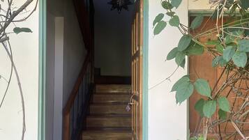 A staircase with a wooden handrail and a patterned mat at the bottom.