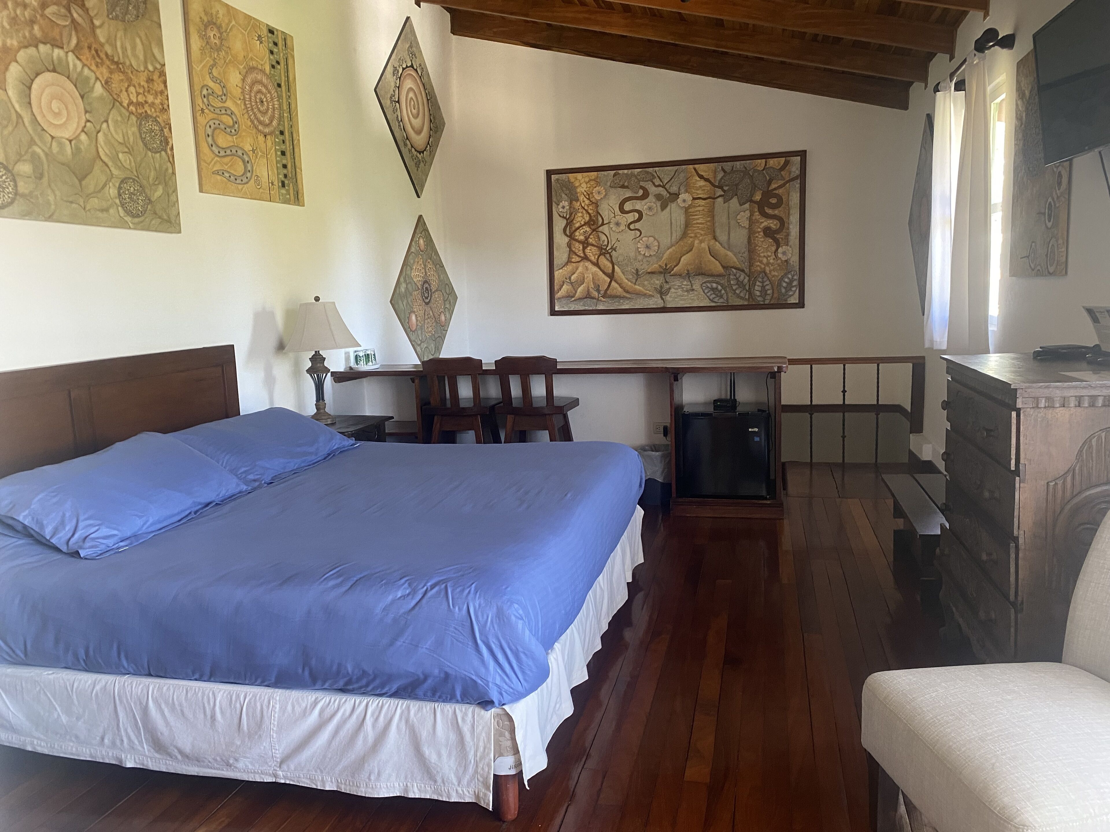 Una camera da letto con un letto grande, una scrivania e una sedia. Sono presenti opere d'arte alle pareti e un camino.