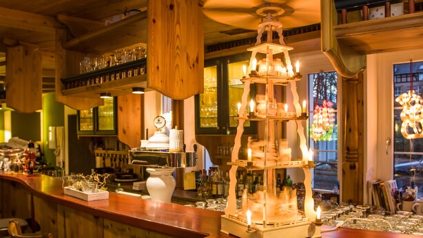 A bar area with wooden decor, a tiered candle holder, and various glassware on the counter. - Landhotel Gutshof (Hartenstein)