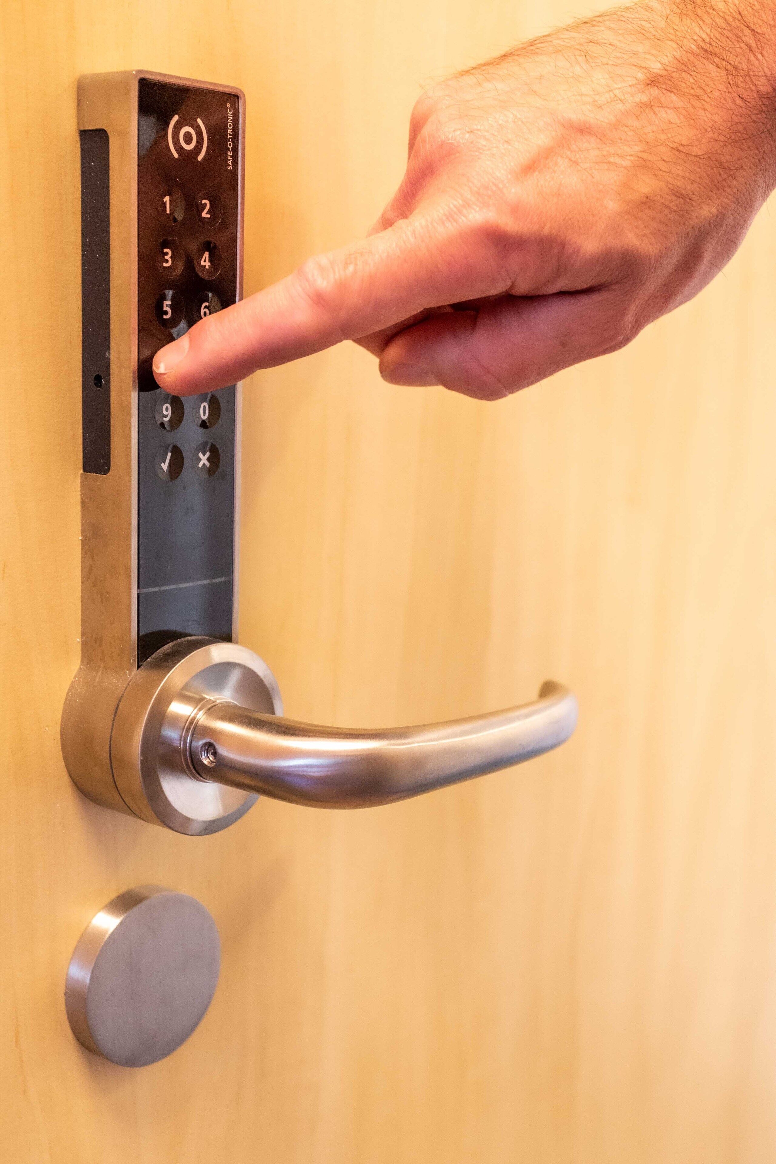 Une main appuyant sur un bouton du clavier d’un système de verrouillage de porte.