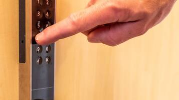Une main appuyant sur un bouton du clavier d’un système de verrouillage de porte.