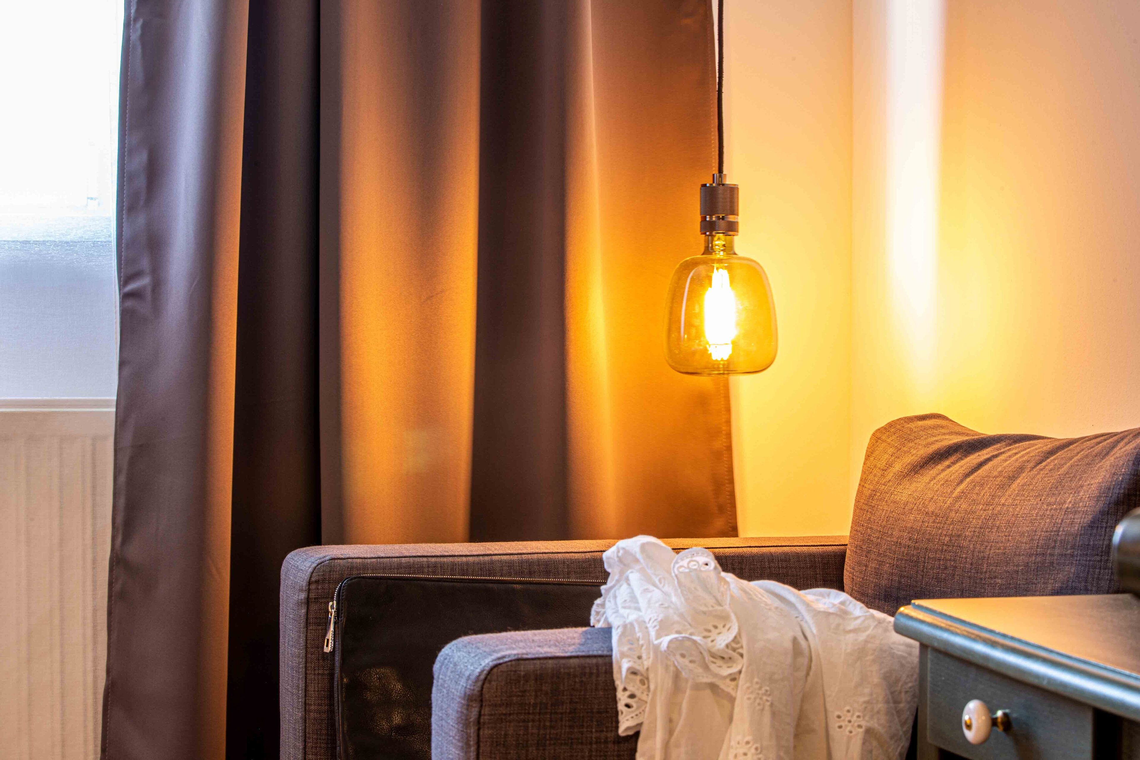 Una habitación con cama, mesita de noche y lámpara.