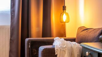 Una habitación con cama, mesita de noche y lámpara.