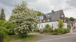 A two-story house with a sloped roof, a visible chimney, and a small tower-like structure on the roof. - Landhotel Gutshof (Hartenstein)