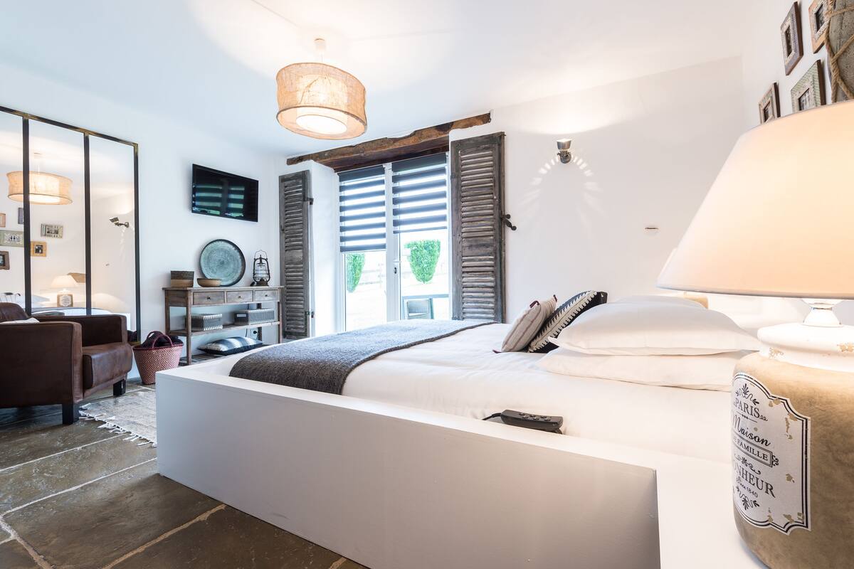 Un dormitorio moderno con una cama grande, una mesita de noche, una lámpara y vistas al exterior.