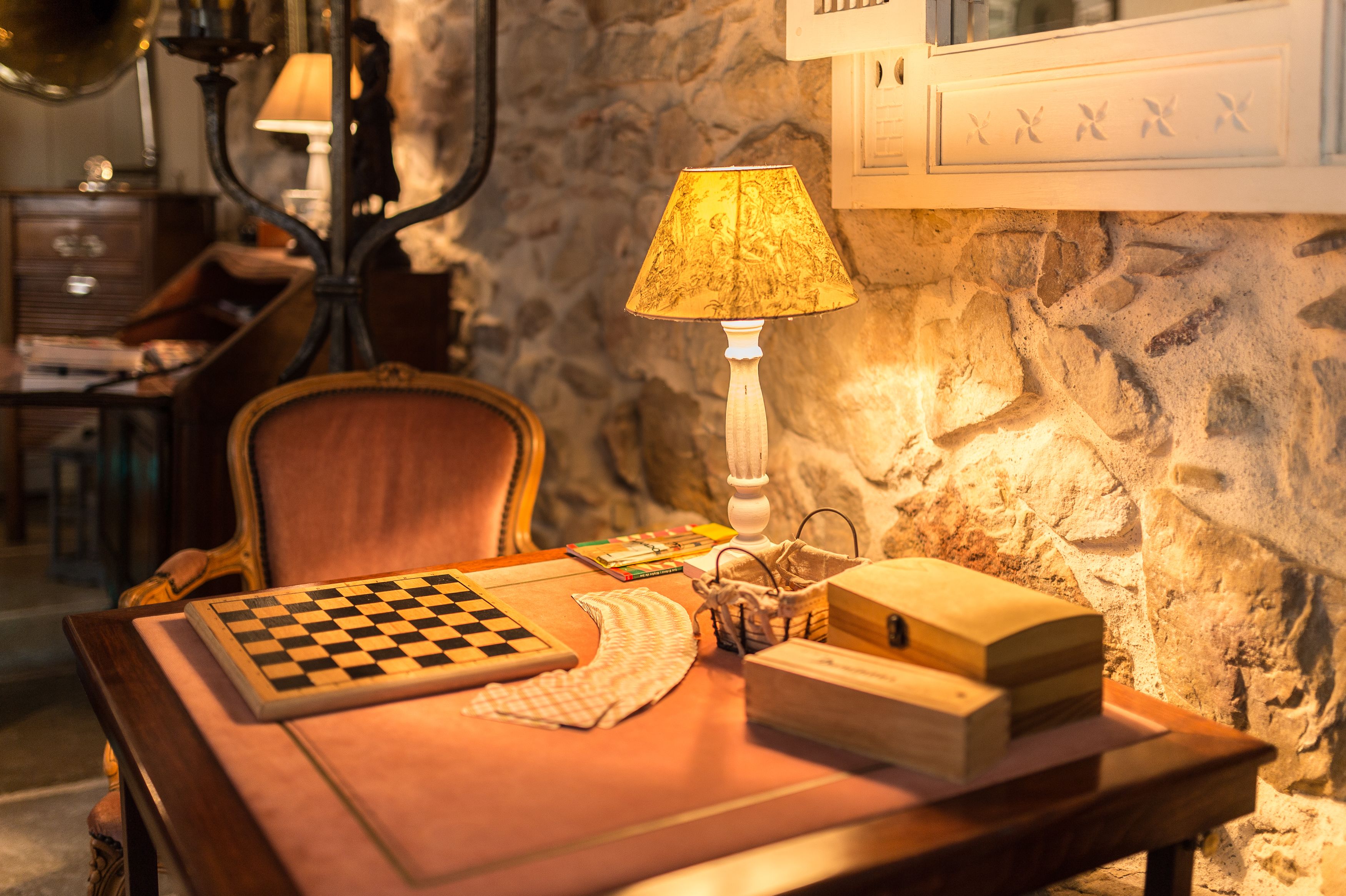 Una mesa de madera con un tablero de ajedrez, una lámpara y una cajita de madera.