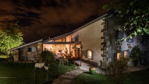 Un edificio de piedra con una escalera de piedra que lleva a una puerta de madera, rodeado de césped y una oveja.