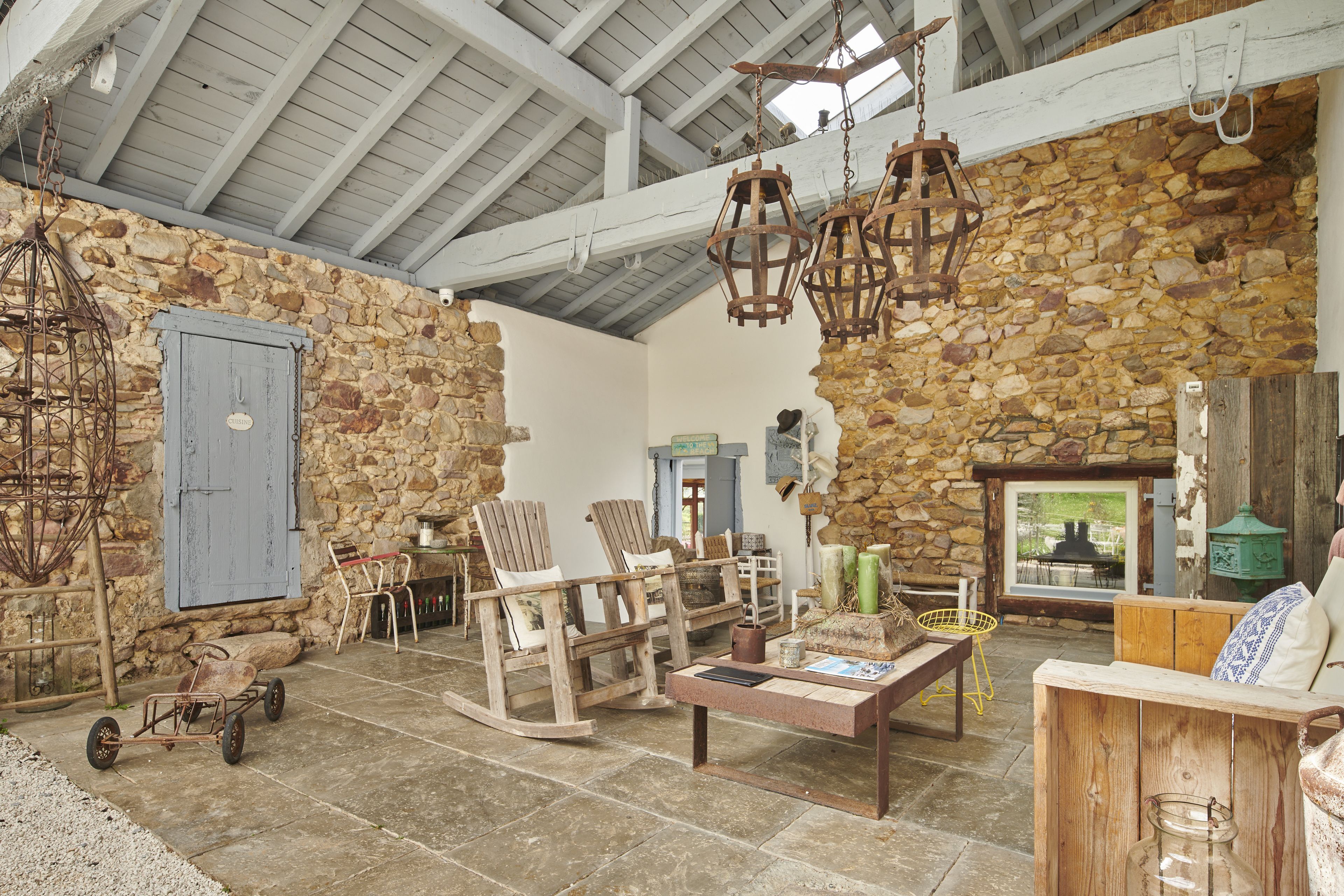 A rustic interior with stone walls, wooden furniture, and hanging lanterns.