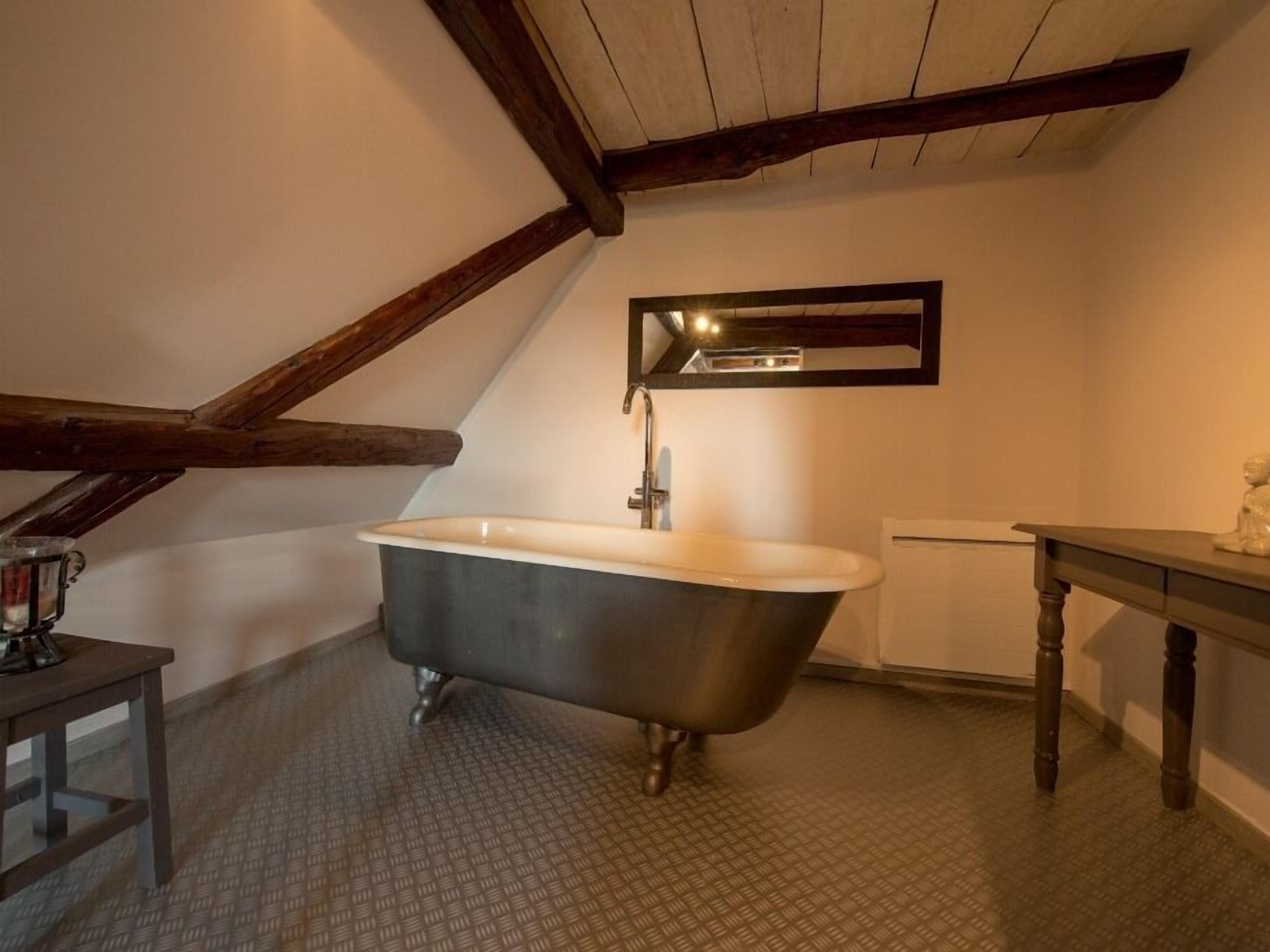 A bathroom with a freestanding bathtub, a small table, and a mirror above the sink.