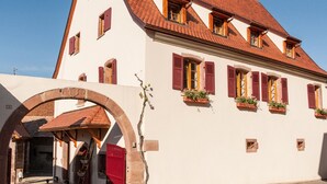 A traditional European building with a red-tiled roof, white walls, and red shutters.
