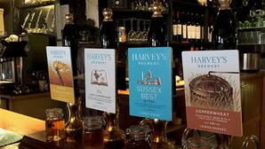 A bar with various beer bottles and glasses, each labeled with the name 'Harvey's Brewery' and different beer types like 'Olympia', 'Sussex Best Bitter', and 'Copper Wheat'. - The Rose & Crown (Etchingham)