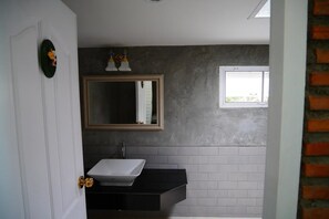 Ein Badezimmer mit einer weißen Tür, einem schwarzen Waschbecken, einem Spiegel und einem Fenster.