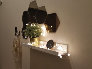 A shelf with a potted plant, a clock, and string lights. - Dheva Resort (Khlong Khuean)