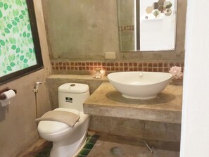 A bathroom with a toilet, a sink, and a mirror. - Dheva Resort (Khlong Khuean)