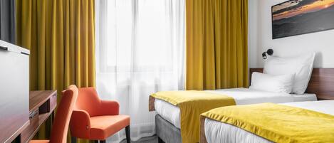 Habitación de hotel con dos camas, un escritorio y una silla naranja.