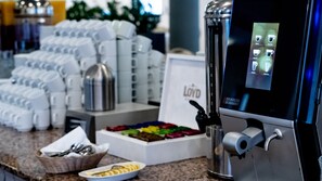 A coffee station with a coffee machine, cups, and a sign that reads "Loyd".