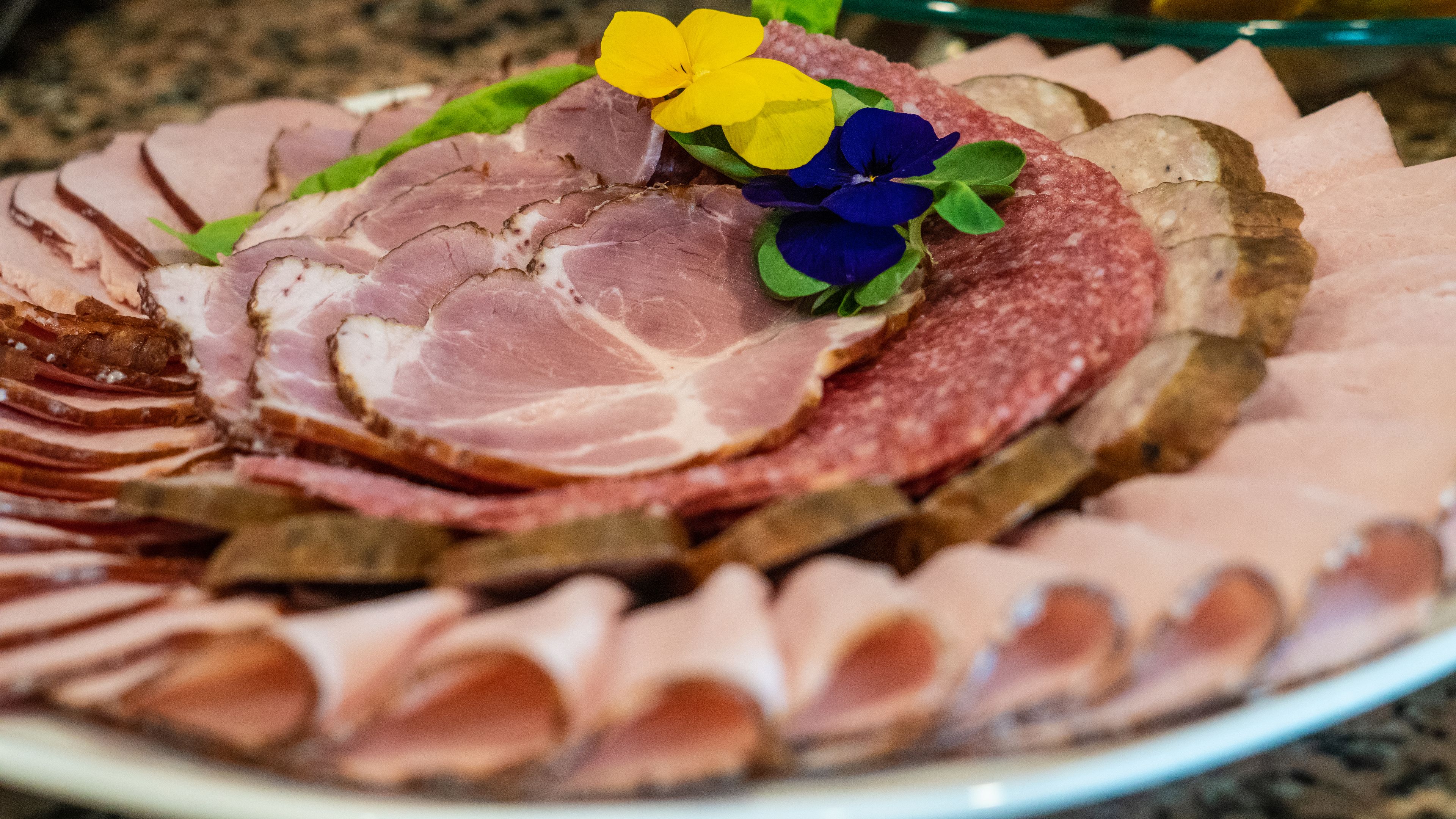 A platter of sliced meats and flowers.
