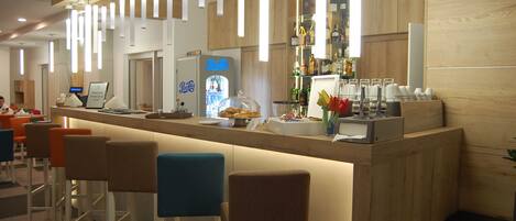A modern bar area with a counter, stools, and a neon sign.