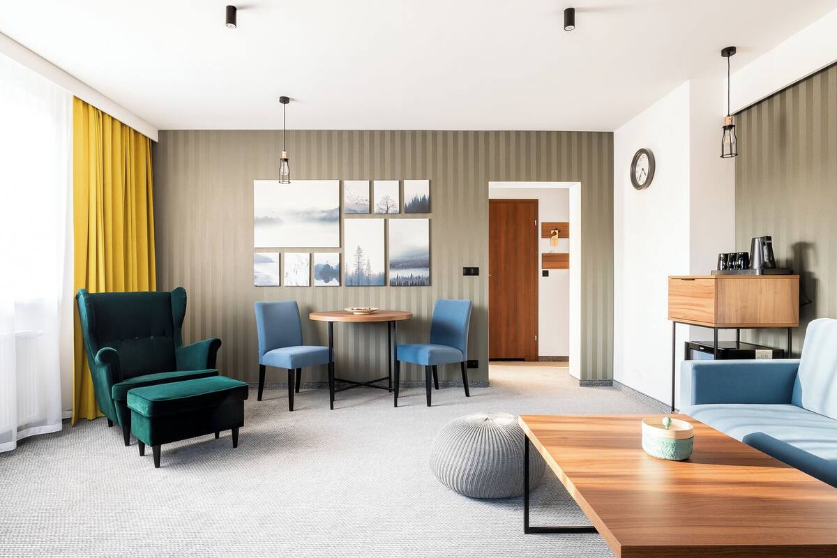 Una habitación de hotel moderna con una zona de estar, una mesa de comedor y un sofá.