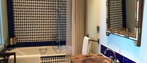 Un baño con bañera, lavamanos de madera y ducha.