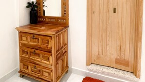 Une commode en bois avec un miroir, une porte et un tapis rouge.