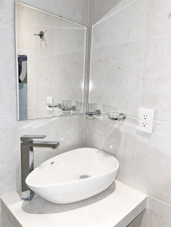 A modern bathroom with a white sink, a glass shower enclosure, and a mirror.