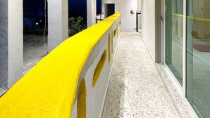 Un couloir avec des rampes jaunes, une porte en verre et un plafond doté d’un éclairage encastré.