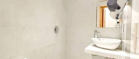 A modern bathroom with a toilet, shower, and sink.