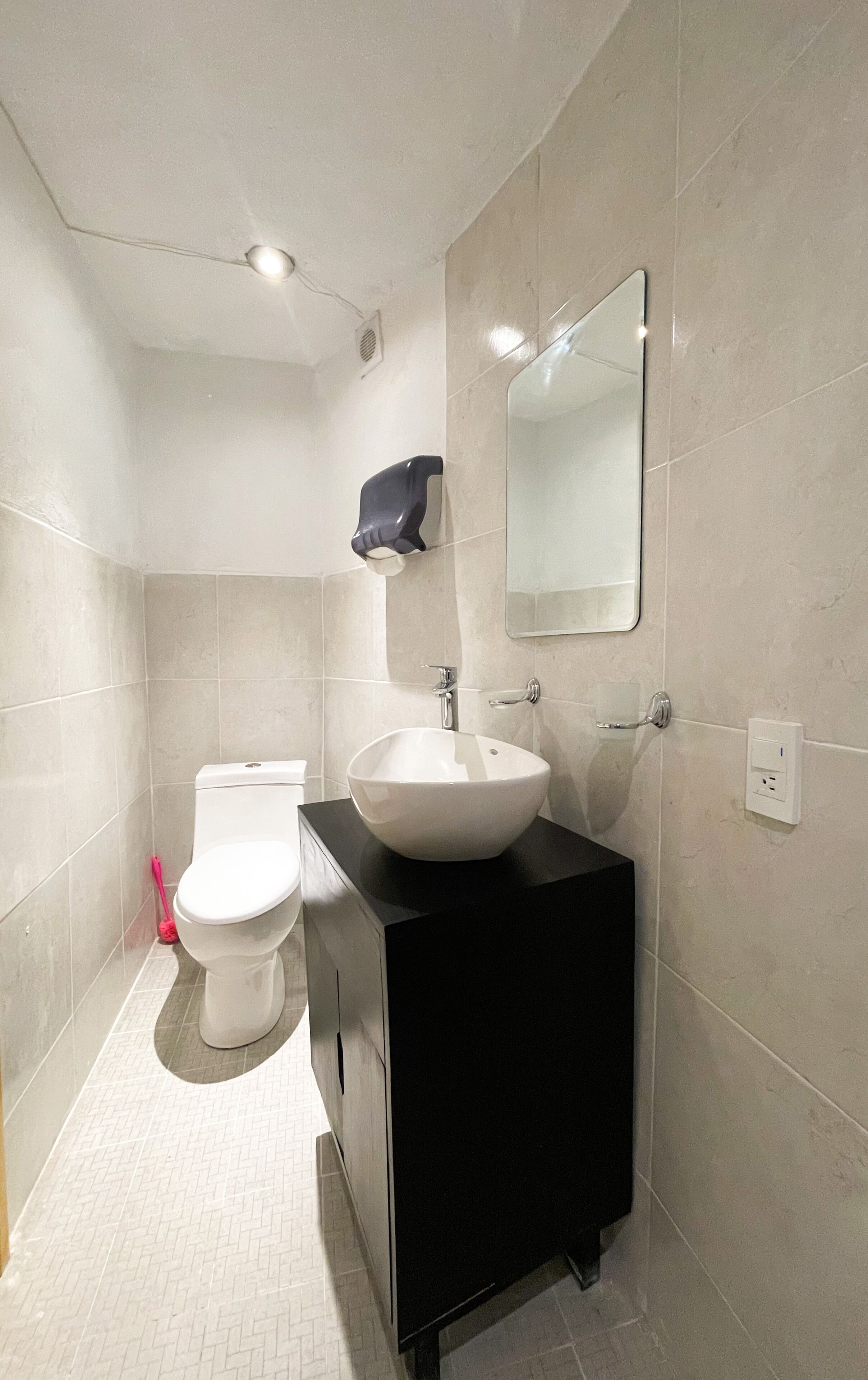 Une salle de bain moderne avec des toilettes blanches, un meuble-lavabo noir et un grand miroir.