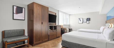 A hotel room with a bed, a sofa, a wardrobe, a TV, and artwork on the walls.