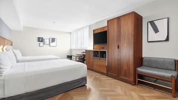 A hotel room with a bed, a desk, a chair, a wardrobe, and a television.