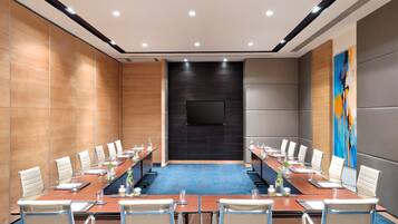 A conference room with a long table, chairs, and a TV screen.