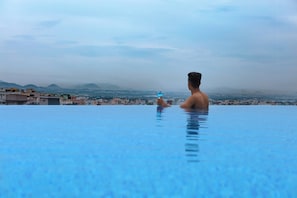 A person in a swimming pool with a cityscape in the background. - Fairfield by Marriott Visakapatnam (Visakhapatnam)