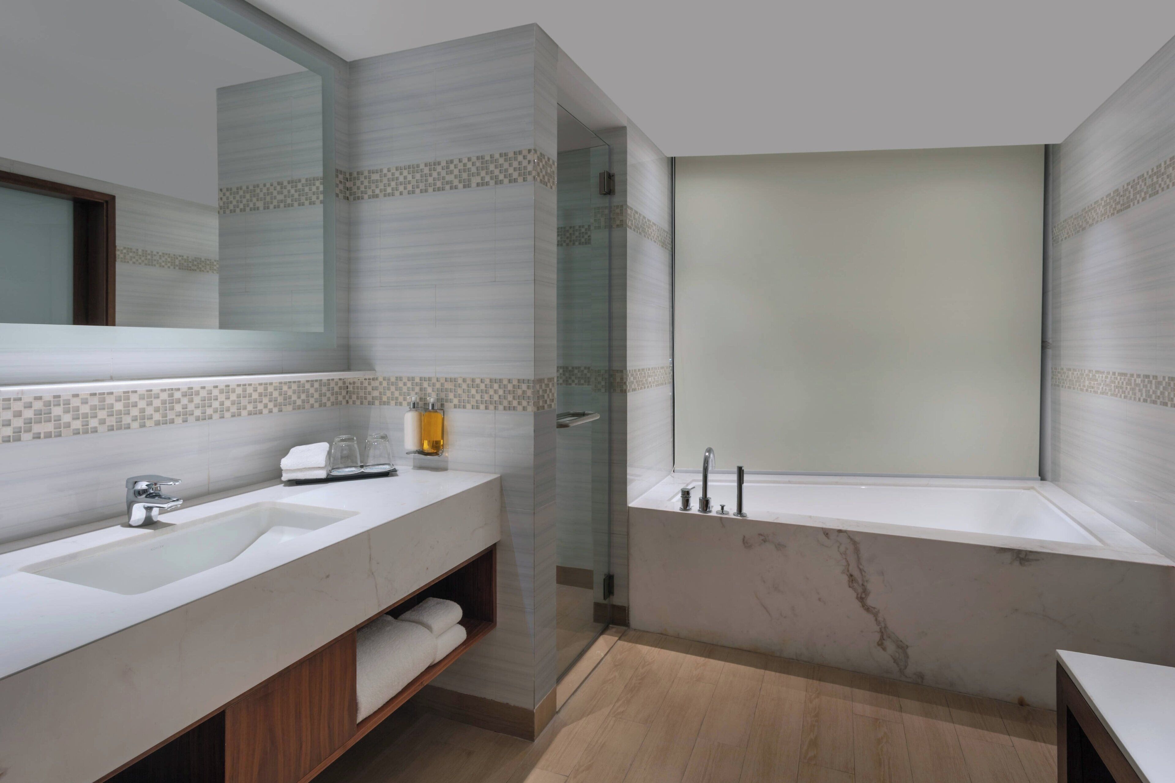 Une salle de bain moderne dotée d’un grand miroir, de deux vasques, d’une baignoire et d’une cabine de douche en verre.