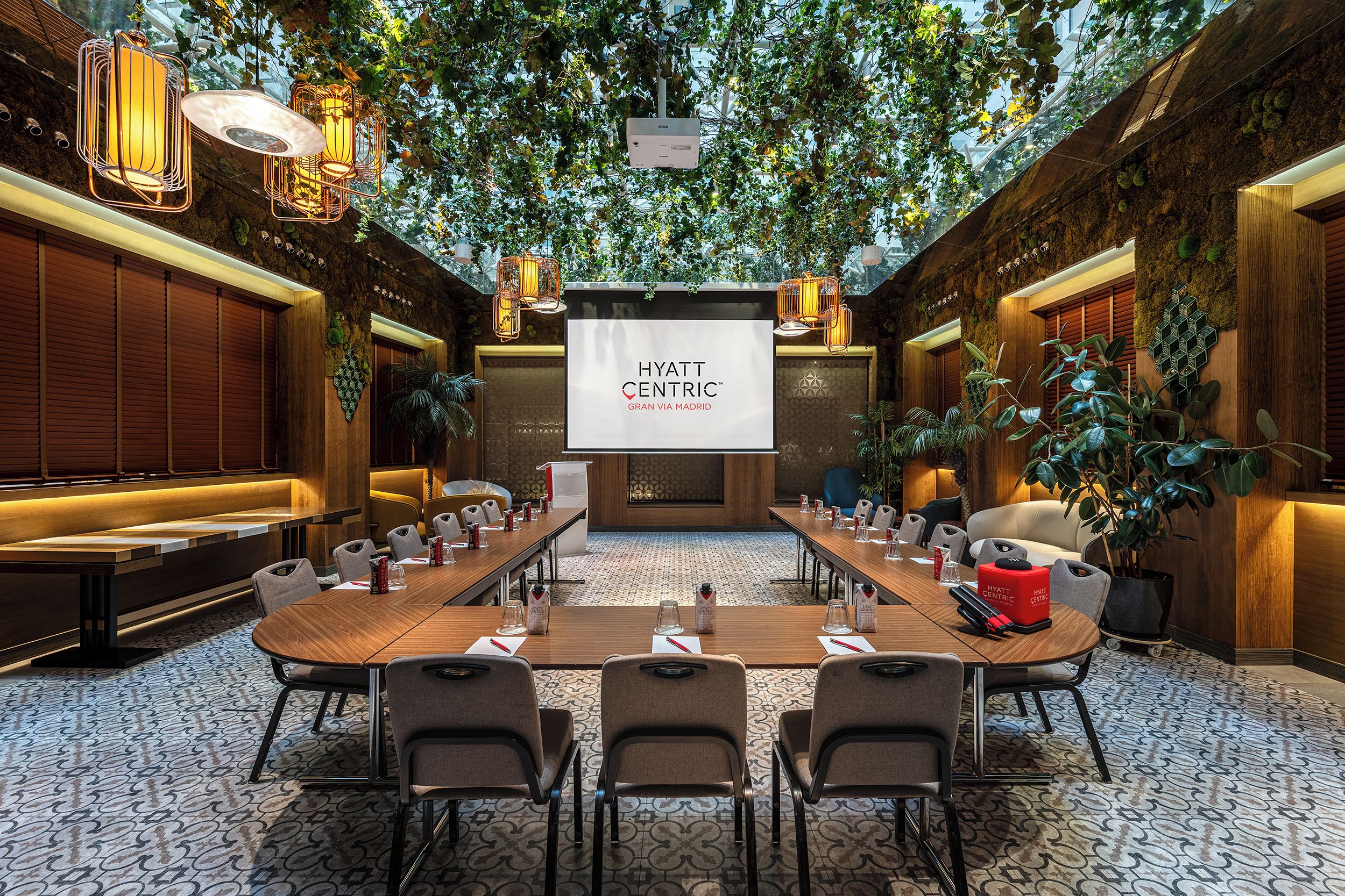 A conference room with a long table, chairs, and a screen displaying 'HYATT CENTRIC GRAN VIA MADRID'.