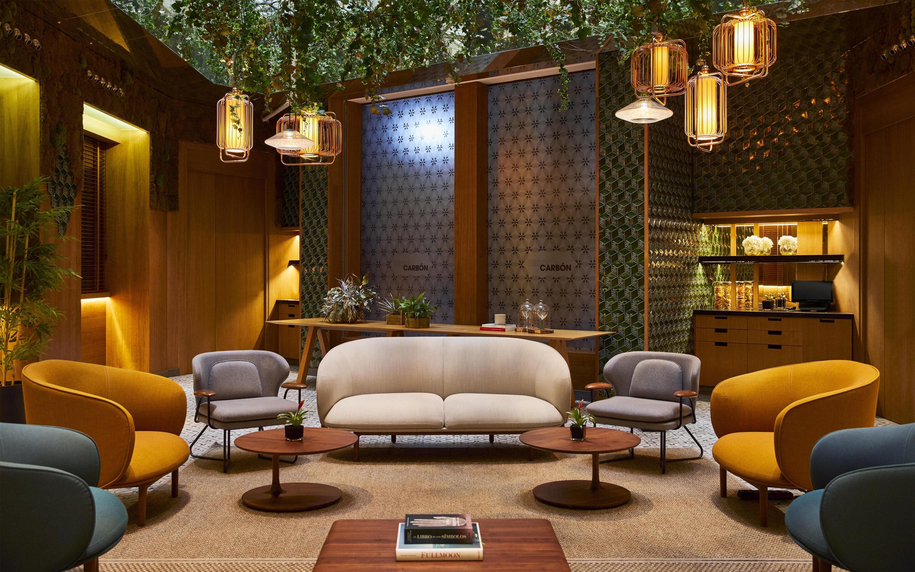 Un interior moderno con sofá, sillones, una mesa de centro e iluminación colgante.