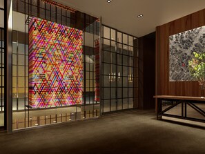 A modern interior with a colorful geometric wall art, a map on the wall, and a wooden table with a vase.