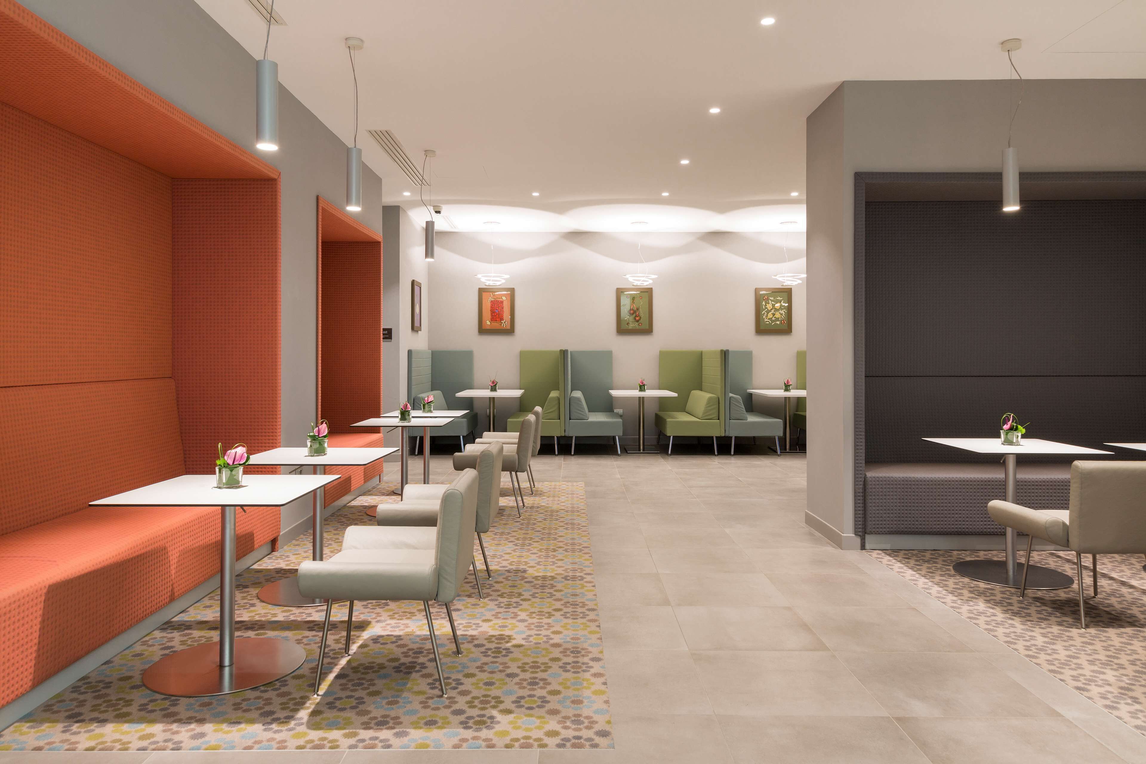 A modern waiting area with seating, tables, and artwork on the walls.