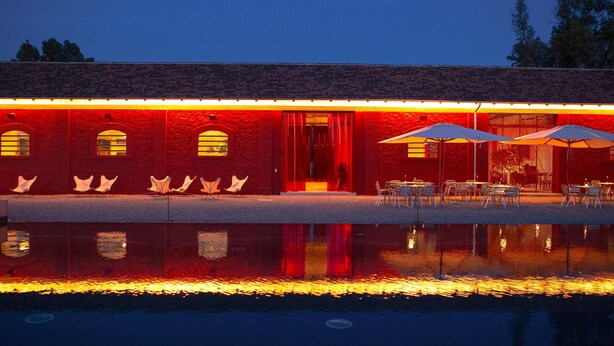 A building with a red facade, outdoor seating, and a pool. - Hampton by Hilton Rome East (Rome)
