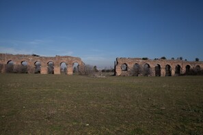 A historical stone bridge with multiple arches spanning a grassy field.