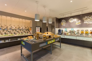 A modern hotel lobby with a buffet area featuring various food items and a wall with motivational quotes.