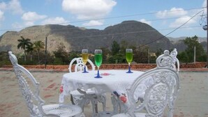 Une table entourée de chaises blanches décorées et recouverte d’une nappe, le tout mis en valeur par un paysage montagneux en arrière-plan.