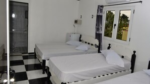 Une chambre d’hôtel avec deux lits simples, une fenêtre donnant sur un paysage agréable, une porte et un sol à carreaux.