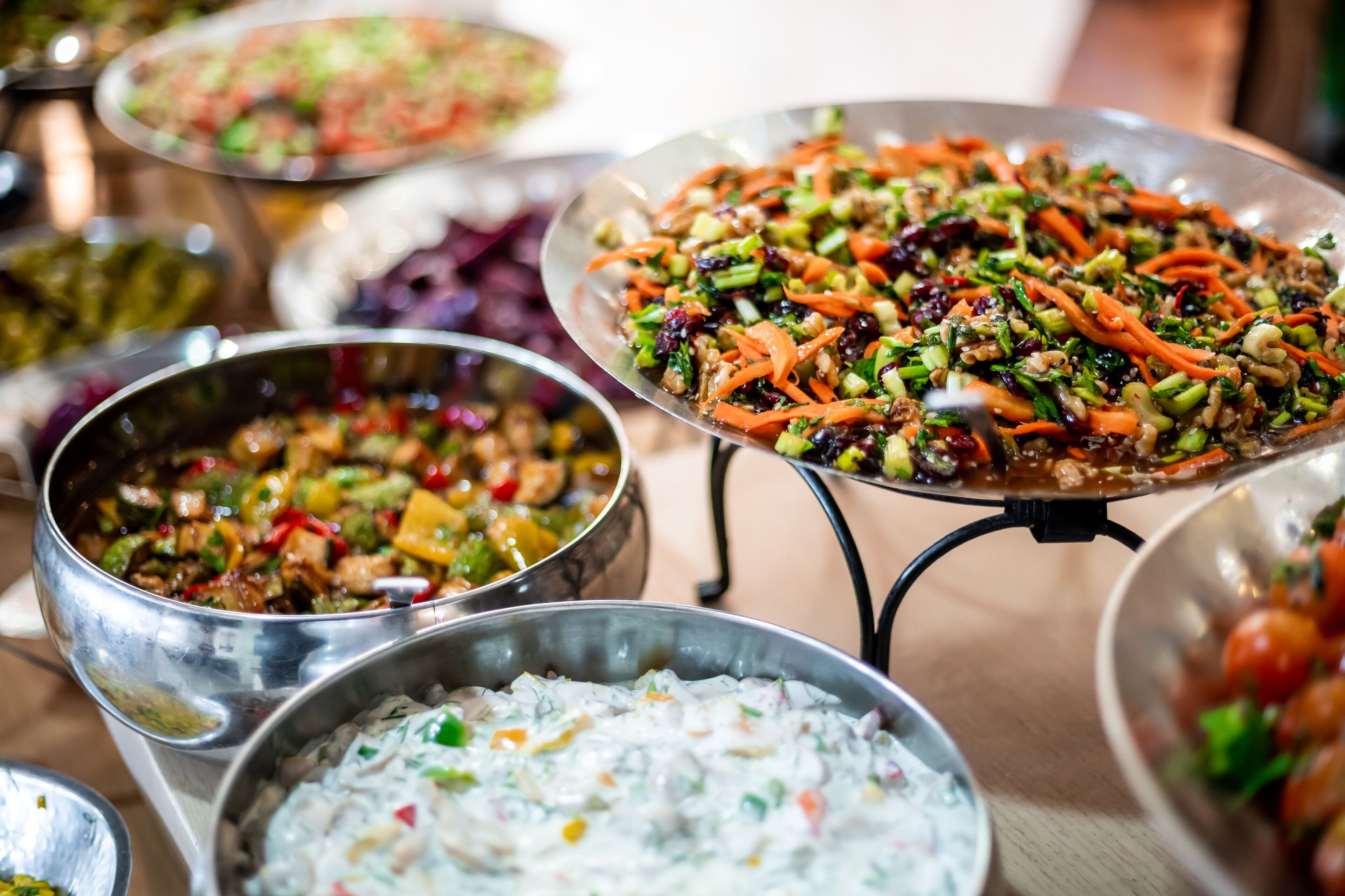 A variety of dishes on metal serving platters, including salads and a creamy dip.
