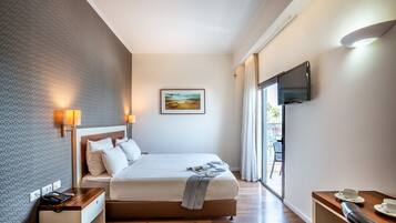 A hotel room with a bed, bedside table, lamp, TV, and a view of the outdoors.