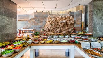 Un buffet proposant une variété de plats, avec un grand rocher en arrière-plan.